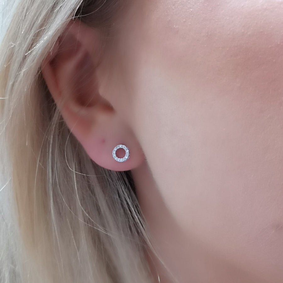 Close-up of an ear wearing a small round earring with a blurred background