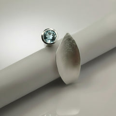 silver ring reminicent of a leaf set with blue topaz