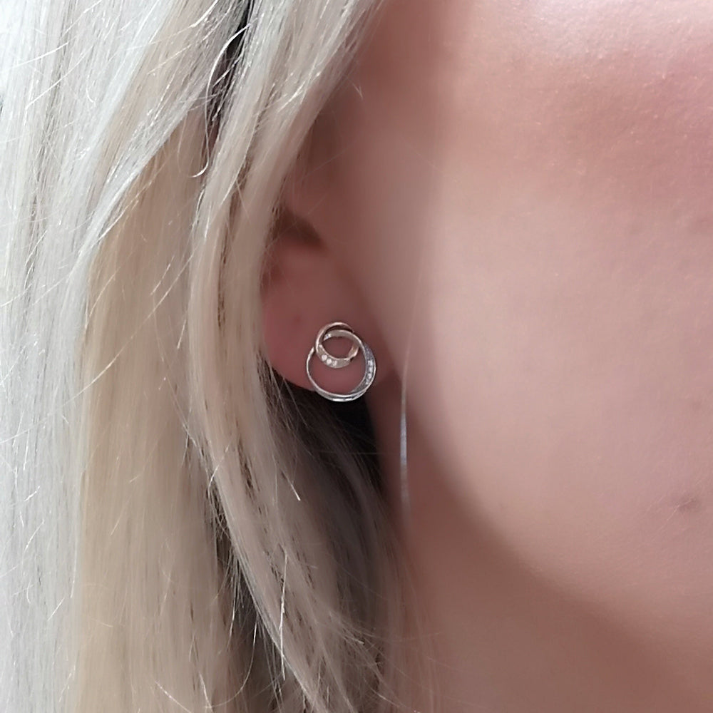 Close-up of an ear with stud white an yllow gold earring blonde hair.