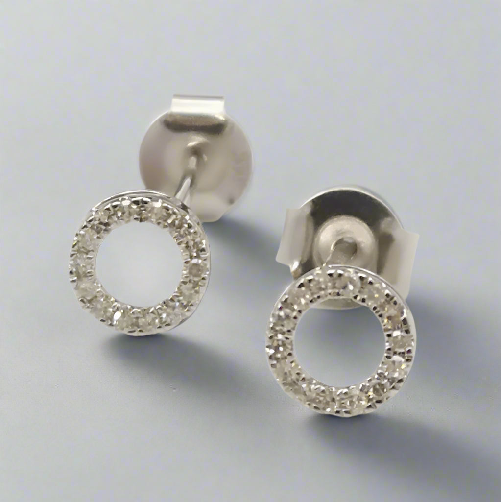 Pair of silver circle  diamond earrings on a white background