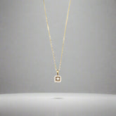 Gold necklace with a diamond pendant on a light gray background