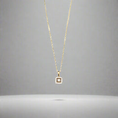 Gold necklace with a diamond pendant on a light gray background