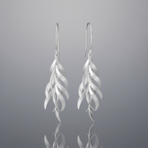 A pair of silver drop earrings with a layered, feather-like wavy design, shown against a plain white background.