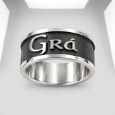 A silver-toned metal ring with a textured black center band featuring the engraved name 'Grá' in polished silver lettering, shown on a clean white background.
