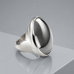 A silver signet ring featuring a large, polished round cabochon gemstone with a dark gray center and bright silver edges, set against a clean white background.