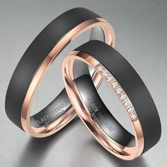 Two black titanium rings with rose gold accents on a white background