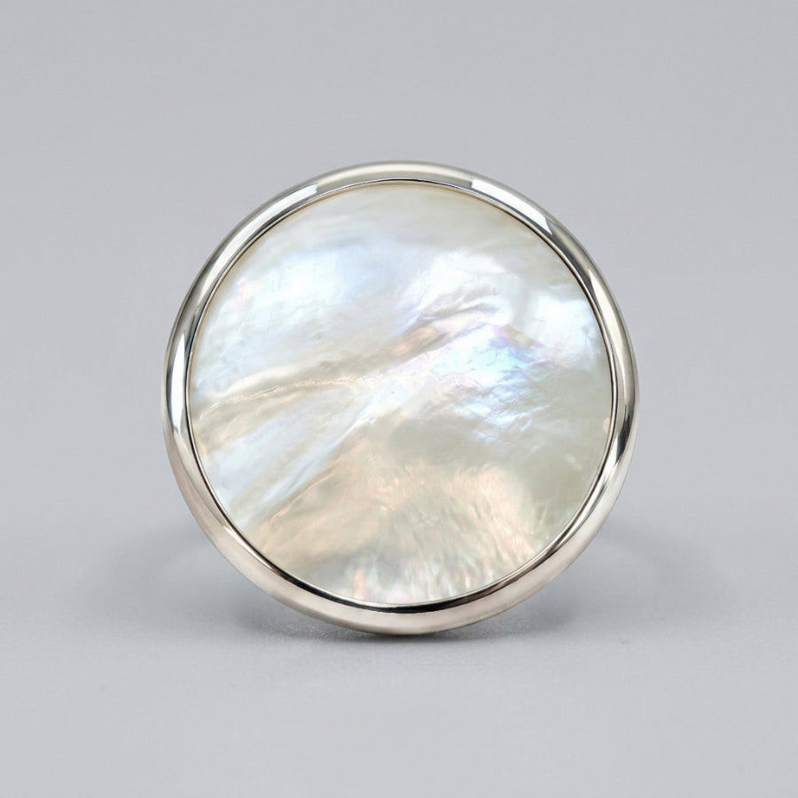 A round silver bezel-set ring featuring a shimmering, iridescent mother-of-pearl inlay, shown on a clean white background.