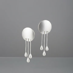 A pair of silver-toned dangle earrings with oval backings and three hanging pearl-like drops each.