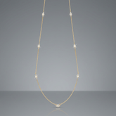 A delicate gold chain necklace with small diamond-like accents spaced along the chain and a small cluster at the center pendant, displayed on a clean white background.