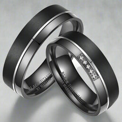 Two black titanium rings with engraved text on a white background