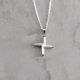 Silver cross necklace on a light gray background