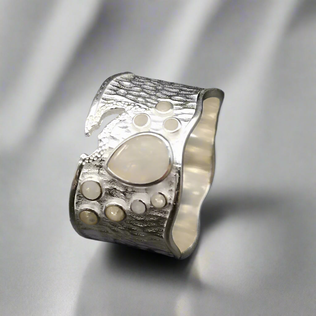 Silver ring with textured design on a dark background
