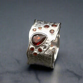 Silver ring with a central red gemstone on a dark background
