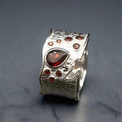 Silver ring with a central red gemstone on a dark background