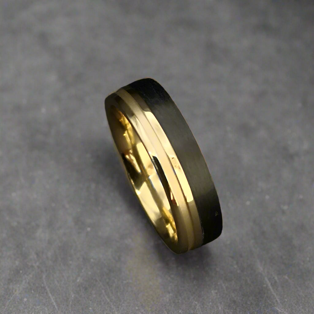 Gold ring with black band on a dark background