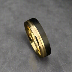 Gold ring with black band on a dark background