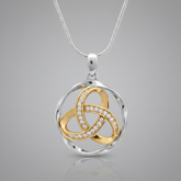 A two-tone silver and gold pendant necklace on a white background. The pendant features a silver-toned circular frame with interwoven gold-toned loops, one of which is lined with small clear stones.