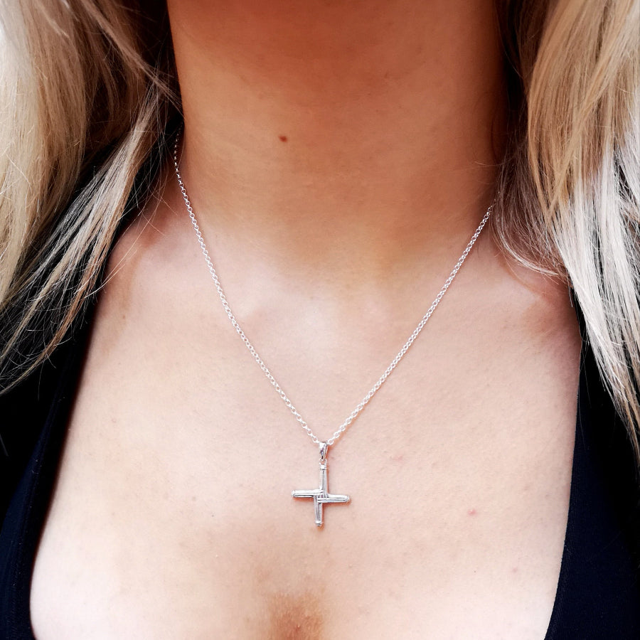 Silver cross necklace on a person with blonde hair