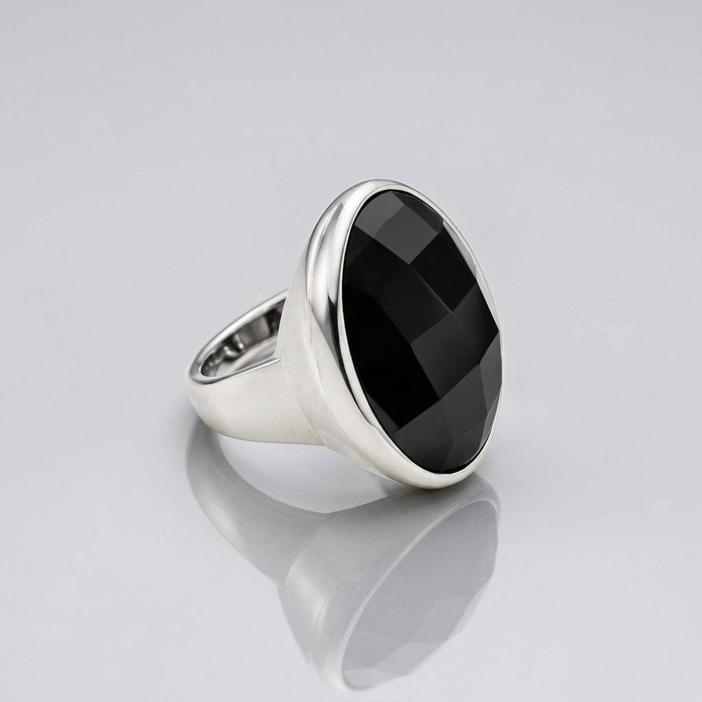 A silver signet-style ring featuring a large, faceted black round gemstone, photographed on a clean white background.