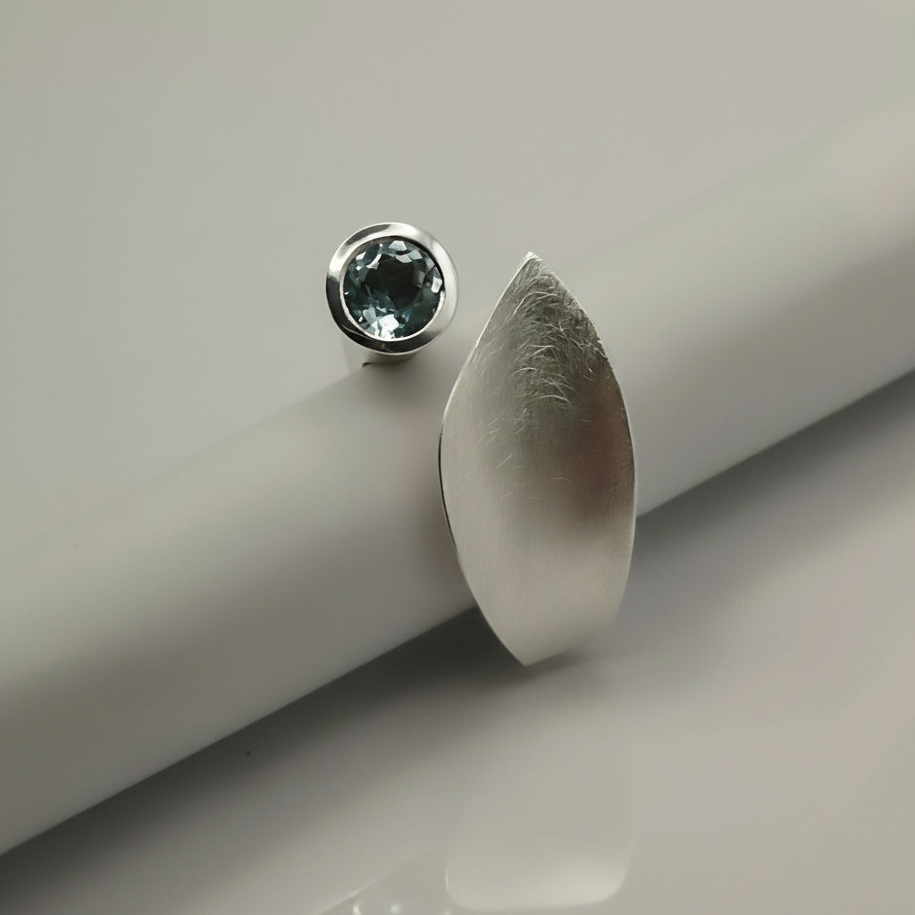 silver ring reminicent of a leaf set with blue topaz