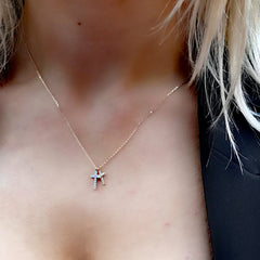 gold cross pendant on womans neck