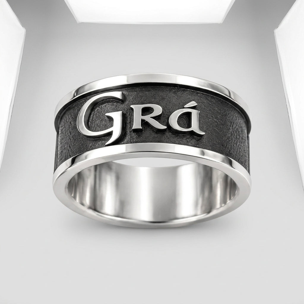 A silver-toned metal ring with a textured black center band featuring the engraved name 'Grá' in polished silver lettering, shown on a clean white background.