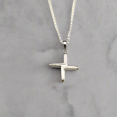 Silver cross necklace on a light gray background