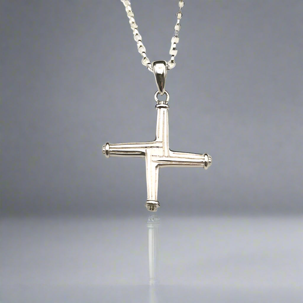 Silver cross pendant on a chain against a light background